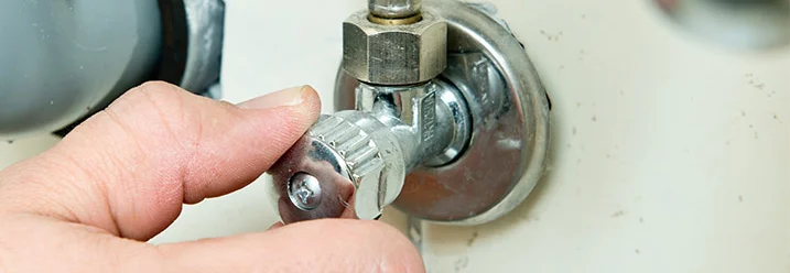 Hand dreht an einem Wasserhahn